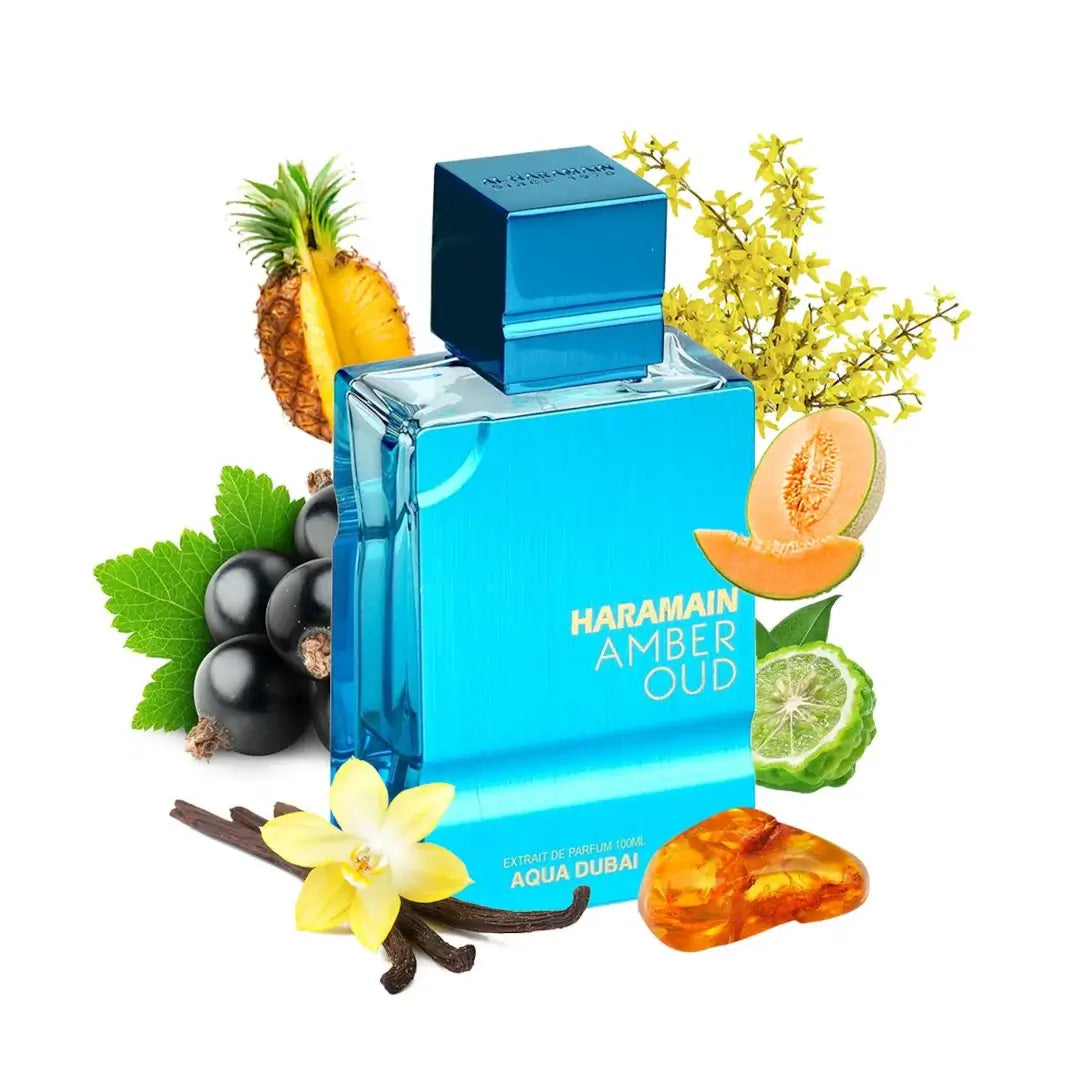 Blue perfume bottle labeled 'Haramain Amber Oud Aqua Dubai' surrounded by fruits, flowers, and leaves on a white background
