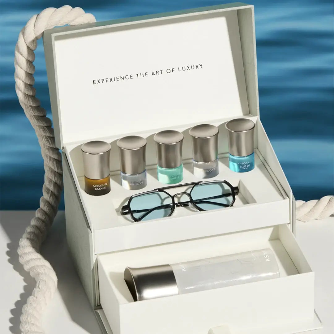 'Aura Collection 35' Luxury travel set with bottles and sunglasses in a white box against a blue water background with 'Assaf' branding