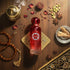 'Bahraini Imperial' Red bottle with intricate design on a wooden surface with decorative elements by Gissah