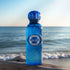 Kuwaiti Imperial EDP Blue bottle with a Gissah brand logo on a beach with ocean in the background