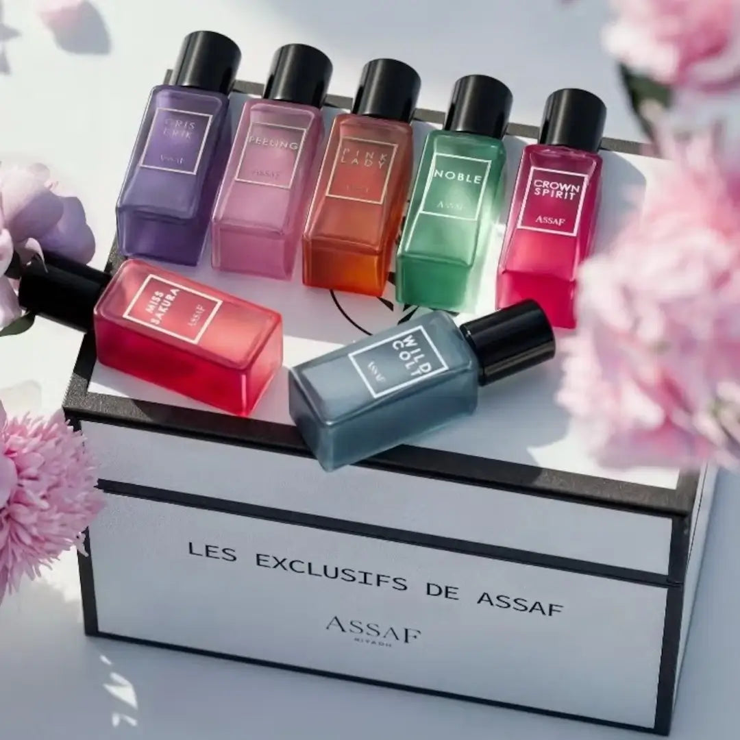 'Les Exclusifs De Assaf' perfume bottles in various colors on a white box with floral background with Assaf branding