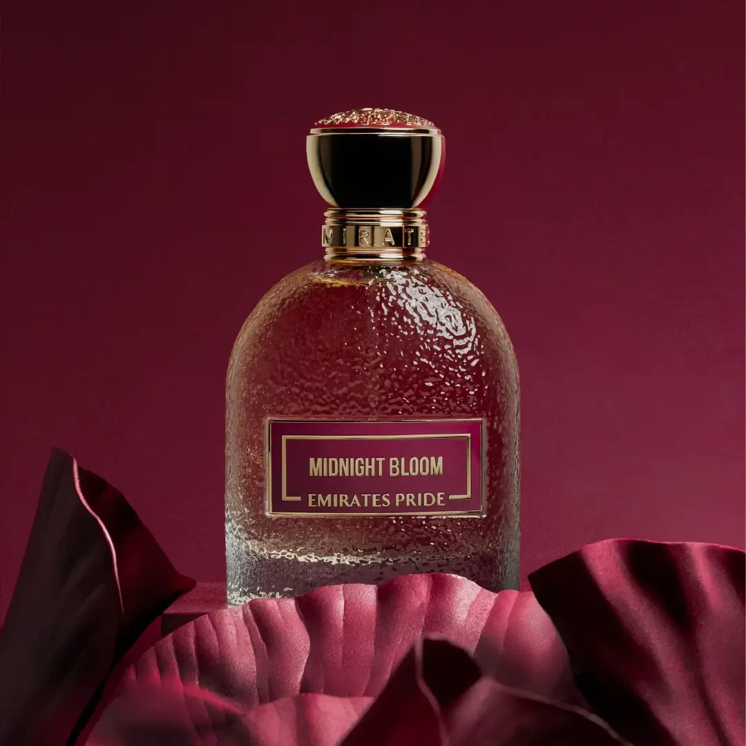Perfume bottle labeled 'Midnight Bloom Emirates Pride' on a red fabric background