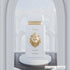 Perfume bottle with gold lion emblem and 'Rey' text with Maison Asrar branding on a white pedestal against an architectural background featured by ArabiaScents
